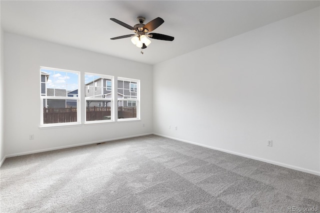 carpeted empty room with a ceiling fan and baseboards