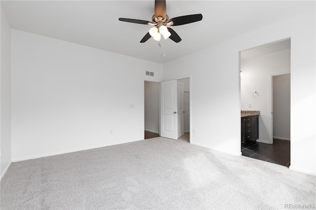 unfurnished bedroom with ceiling fan, connected bathroom, visible vents, baseboards, and dark carpet