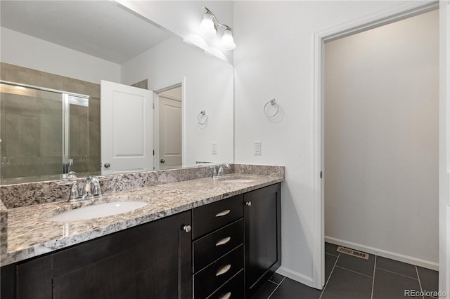 full bath with double vanity, tile patterned flooring, a shower stall, and a sink