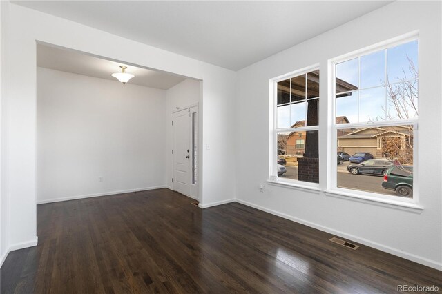 empty room featuring baseboards, visible vents, and wood finished floors