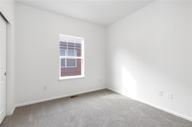 carpeted spare room with visible vents and baseboards