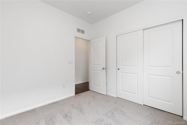 unfurnished bedroom featuring carpet floors, baseboards, visible vents, and a closet