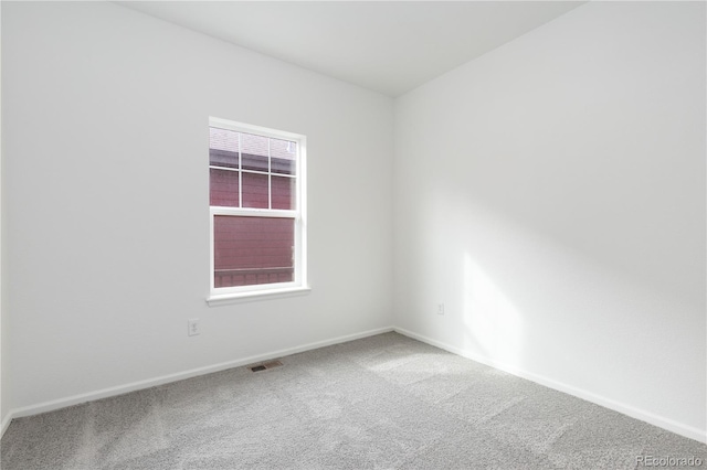 carpeted spare room featuring visible vents and baseboards