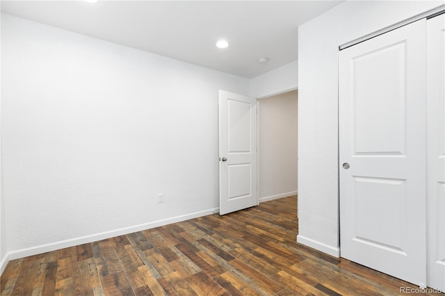 unfurnished bedroom featuring baseboards, dark wood finished floors, and a closet