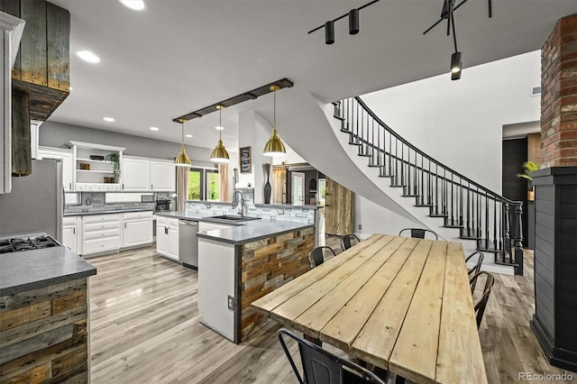kitchen with a sink, stainless steel appliances, decorative backsplash, open shelves, and light wood-type flooring