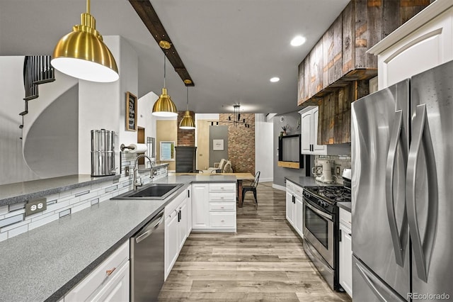 kitchen featuring stainless steel appliances, a sink, light wood-style floors, white cabinets, and recessed lighting