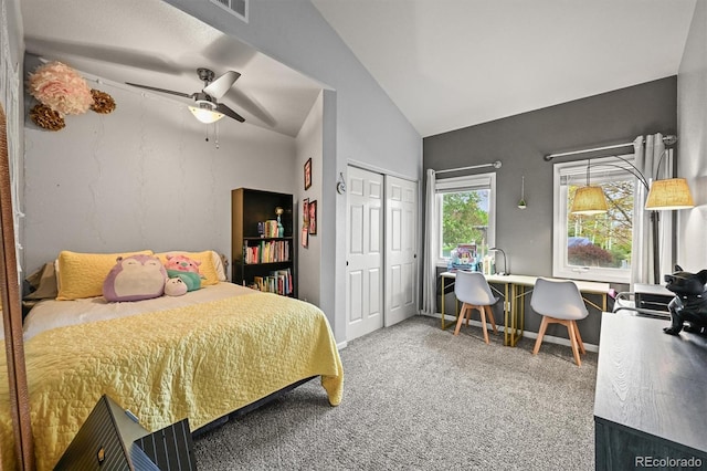 carpeted bedroom with a closet, ceiling fan, and high vaulted ceiling