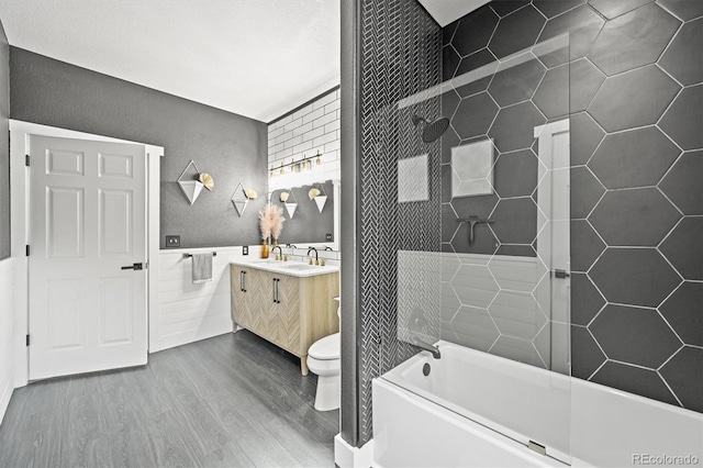 bathroom with wood finished floors, tile walls, vanity, and toilet