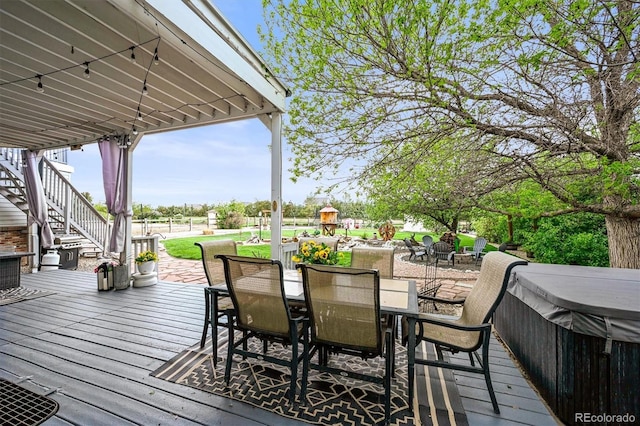 wooden deck featuring outdoor dining space, stairs, and a hot tub