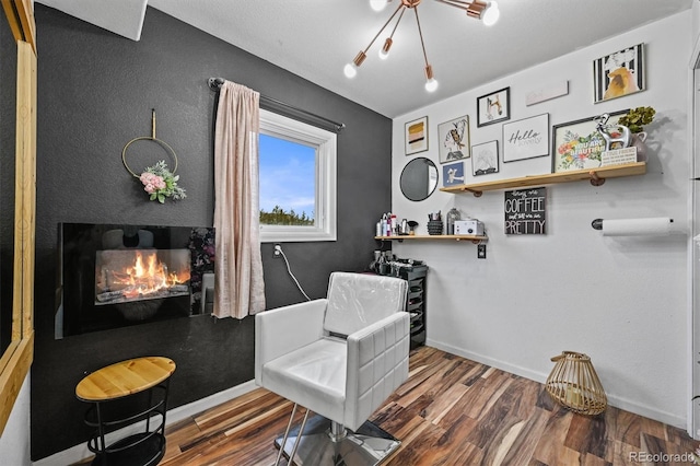 living area with wood finished floors, a warm lit fireplace, and baseboards