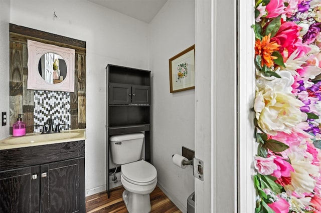 bathroom with wood finished floors, toilet, vanity, and baseboards