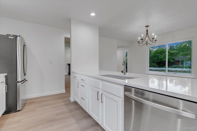 1304 Ceres Dr, Lafayette, CO 80026 - kitchen with appliances with stainless steel finishes, a sink, light countertops, a chandelier, and light wood-style floors