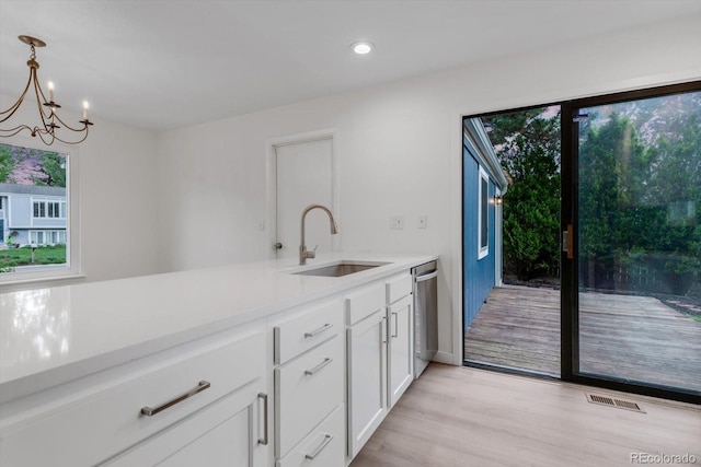 1304 Ceres Dr, Lafayette, CO 80026 - kitchen featuring a sink, light countertops, white cabinets, a chandelier, and light wood-style flooring