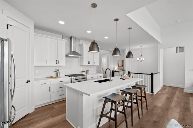 8242 S Pierson St, Littleton, CO 80127 - kitchen featuring a sink, stainless steel appliances, wall chimney range hood, wood finished floors, and visible vents