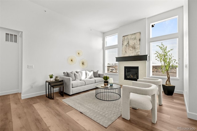 8242 S Pierson St, Littleton, CO 80127 - living room featuring wood finished floors, a towering ceiling, visible vents, baseboards, and a glass covered fireplace