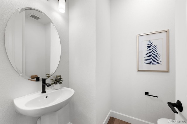 8242 S Pierson St, Littleton, CO 80127 - half bathroom with baseboards, visible vents, a sink, and wood finished floors