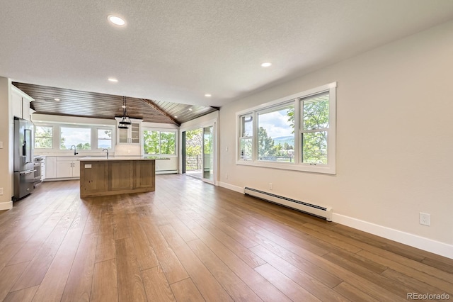 12196 W Belleview Dr, Littleton, CO 80127 - kitchen with baseboard heating, light countertops, baseboards, white cabinets, and lofted ceiling