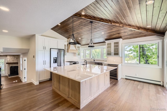 12196 W Belleview Dr, Littleton, CO 80127 - kitchen with beverage cooler, baseboard heating, premium range hood, appliances with stainless steel finishes, and light wood finished floors