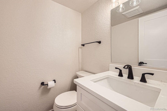 12196 W Belleview Dr, Littleton, CO 80127 - bathroom featuring a textured wall, toilet, and vanity