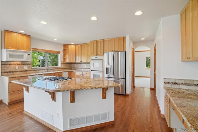 2247 Eagles Nest Dr, Lafayette, CO 80026 - kitchen with stainless steel appliances, a kitchen island, a breakfast bar area, arched walkways, and recessed lighting