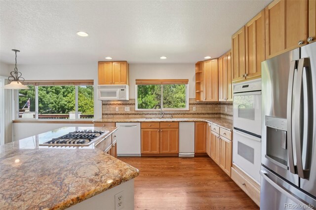2247 Eagles Nest Dr, Lafayette, CO 80026 - kitchen featuring stainless steel appliances, light wood-style flooring, backsplash, a textured ceiling, and light stone counters