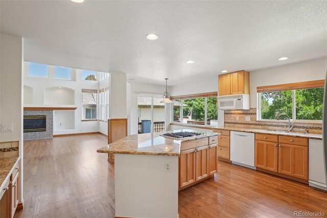 2247 Eagles Nest Dr, Lafayette, CO 80026 - kitchen featuring white appliances, a glass covered fireplace, healthy amount of natural light, light wood-style flooring, and recessed lighting