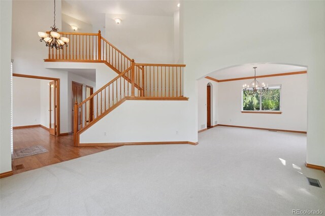 2247 Eagles Nest Dr, Lafayette, CO 80026 - unfurnished living room featuring a chandelier, carpet flooring, arched walkways, stairs, and a high ceiling
