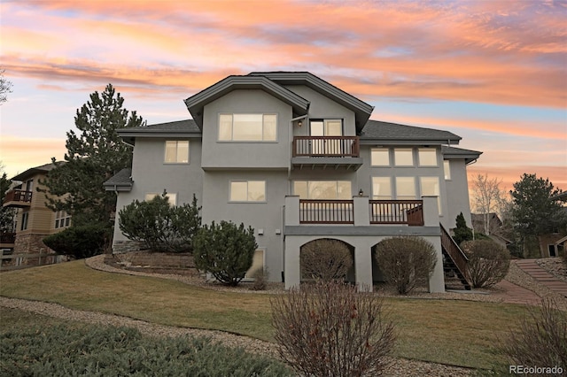 2247 Eagles Nest Dr, Lafayette, CO 80026 - back of house at dusk featuring a balcony, a yard, and stucco siding