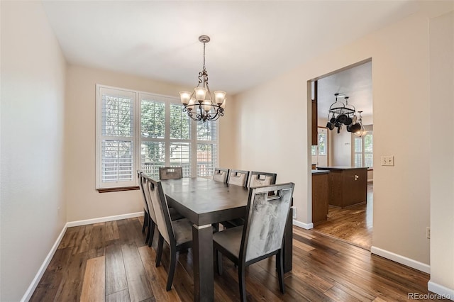 dining area with dark wood-type flooring and a notable chandelier