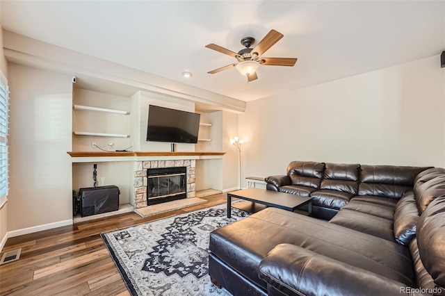 living room with a stone fireplace, hardwood / wood-style floors, and ceiling fan