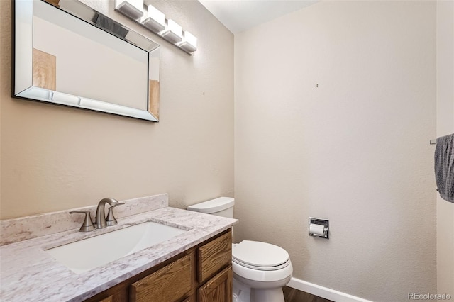 bathroom with vanity, toilet, and hardwood / wood-style flooring