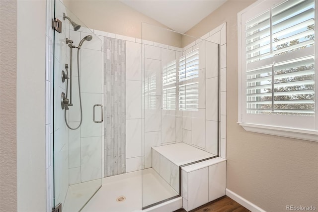 bathroom with lofted ceiling, hardwood / wood-style flooring, and a shower with shower door