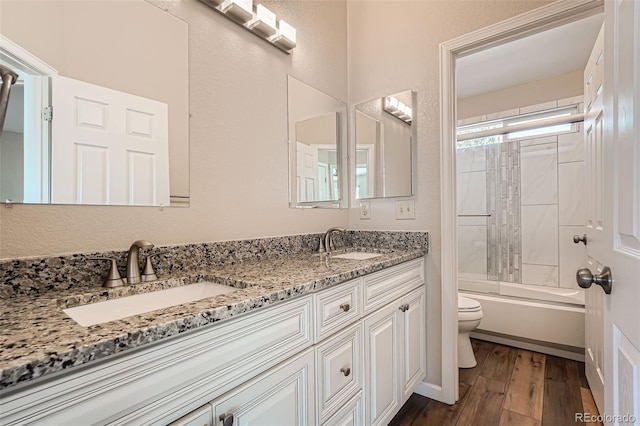 full bathroom featuring washtub / shower combination, hardwood / wood-style flooring, vanity, and toilet