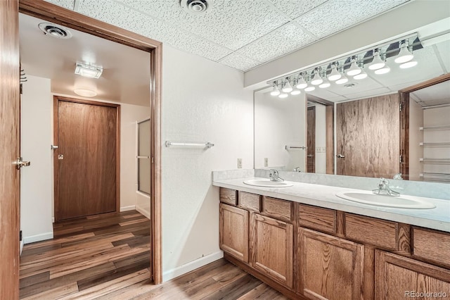 bathroom featuring a paneled ceiling, vanity, a shower with shower door, and hardwood / wood-style flooring