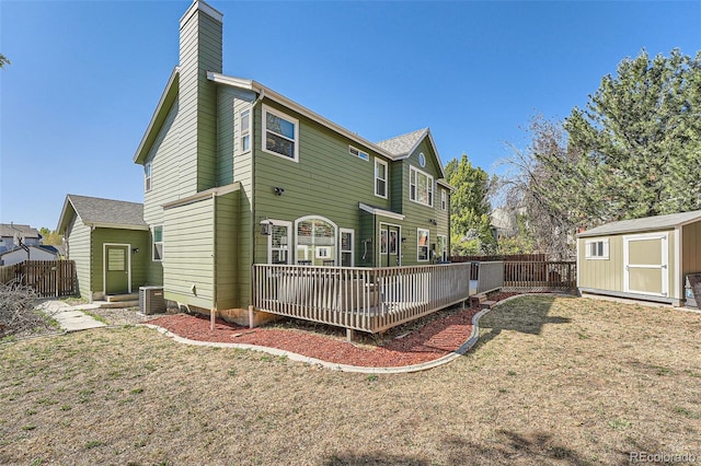 back of property with a storage shed, central AC unit, a deck, and a lawn