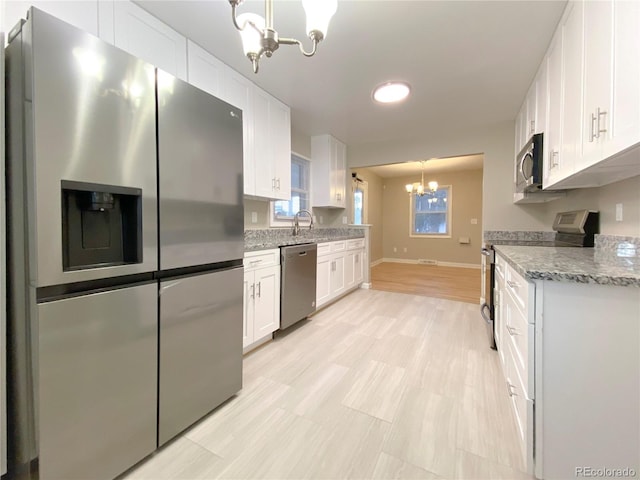 kitchen featuring white cabinets, stainless steel appliances, a chandelier, and decorative light fixtures