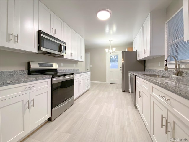 kitchen with appliances with stainless steel finishes, a chandelier, and white cabinetry