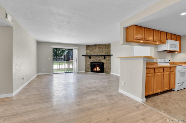 18034 E Ohio Ave Unit 104, Aurora, CO 80017 - kitchen featuring white appliances, a fireplace, light wood finished floors, open floor plan, and light countertops