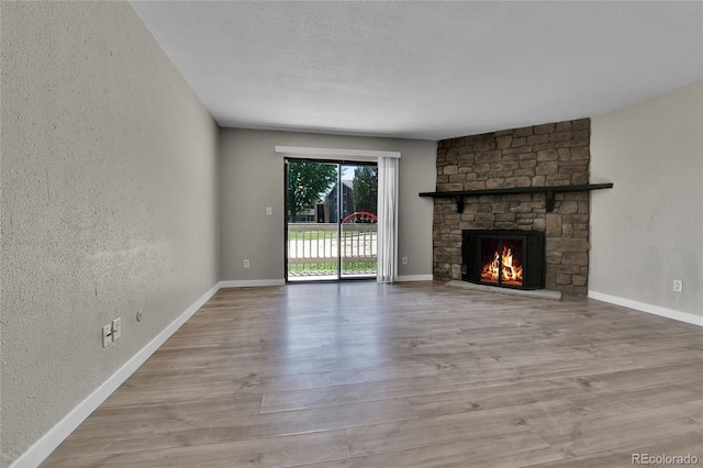 18034 E Ohio Ave Unit 104, Aurora, CO 80017 - unfurnished living room with a textured wall, wood finished floors, a fireplace, and a textured ceiling