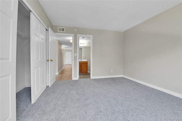 18034 E Ohio Ave Unit 104, Aurora, CO 80017 - unfurnished bedroom with carpet flooring, a textured ceiling, connected bathroom, and a closet