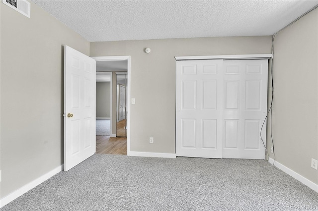 18034 E Ohio Ave Unit 104, Aurora, CO 80017 - unfurnished bedroom featuring carpet floors, a textured ceiling, and a closet