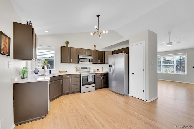 kitchen with stainless steel appliances, light countertops, light wood-style floors, and a sink