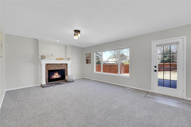 unfurnished living room with carpet, a brick fireplace, and a healthy amount of sunlight