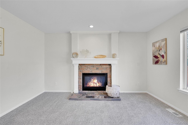 unfurnished living room featuring a brick fireplace, baseboards, and carpet