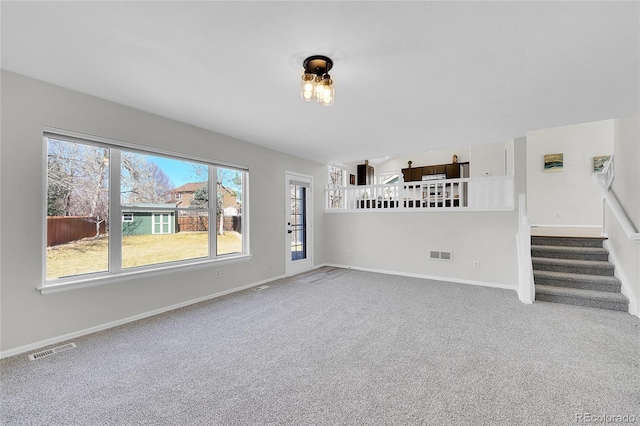 unfurnished living room featuring stairs, carpet, visible vents, and baseboards