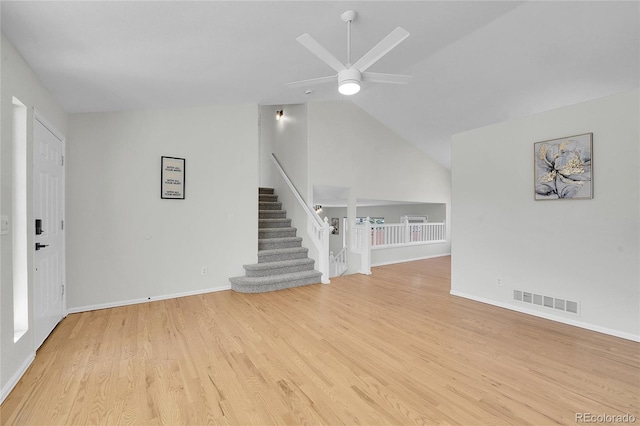 unfurnished living room with a ceiling fan, visible vents, lofted ceiling, stairs, and light wood-type flooring