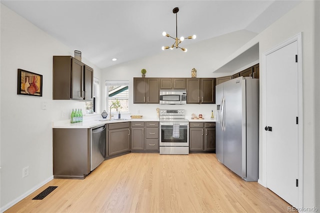 kitchen with visible vents, lofted ceiling, a sink, appliances with stainless steel finishes, and a notable chandelier