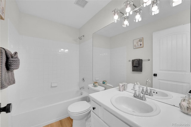 bathroom with vanity, wood finished floors, visible vents, shower / bathing tub combination, and toilet