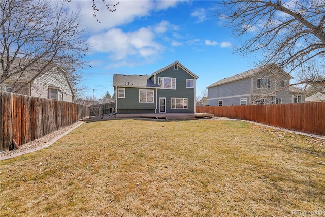 back of property with a yard, a wooden deck, and a fenced backyard