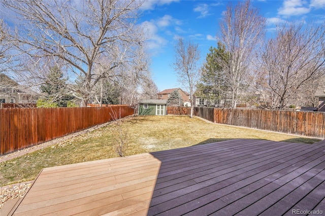 wooden deck with a storage shed, an outbuilding, a yard, and a fenced backyard